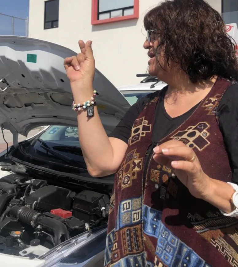 Instructora explicando el motor de un auto durante el curso de mecánica