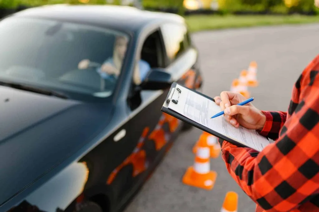 Instructor con lista de evaluación junto a alumna en el auto